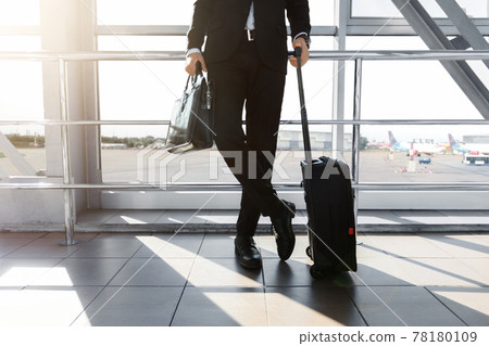 Cropped of rich businessman standing by window in airport 78180109