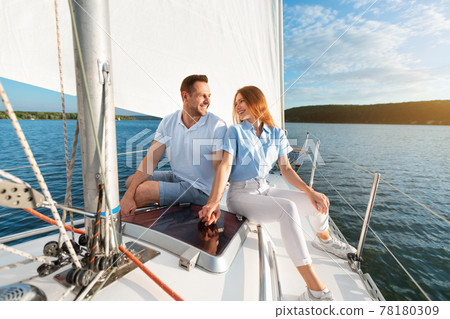 Couple Holding Hands Sitting On Sailboat Deck Enjoying Sailing Tour Couple Holding Hands Sitting On Sailboat Deck Enjoying Sailing Tour 78180309