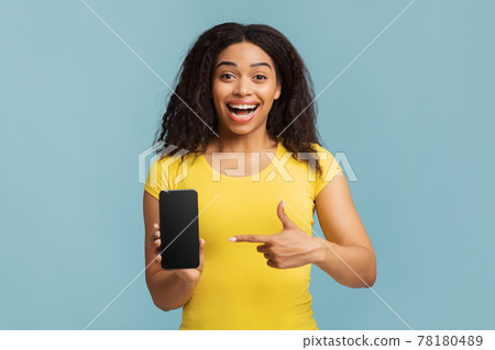 Joyful black lady pointing at smartphone with blank screen on blue studio background, mockup for mobile app design Joyful black lady pointing at smartphone with blank screen on blue studio background, mockup for mobile app design 78180489