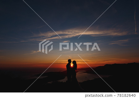 Silhouettes of the bride and groom who are embracing on Mount Lovcen overlooking the Bay of Kotor at sunset Silhouettes of the bride and groom who are embracing on Mount Lovcen overlooking the Bay of Kotor at sunset 78182640