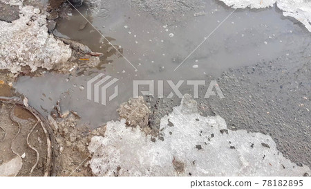 The texture of a muddy puddle with snow, ice and debris, spring snowmelt, outdoor stream The texture of a muddy puddle with snow, ice and debris, spring snowmelt, outdoor stream 78182895