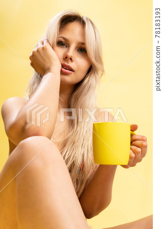 A girl sitting on the floor with her feet cross-legged keeps her head on a beautiful yellow background with a cup in hand yellow or pink and red yellow sexy, pretty female body skin person, sunglasses A girl sitting on the floor with her feet cross-legged keeps her head on a beautiful yellow background with a cup in hand yellow or pink and red yellow sexy, pretty female body skin person, sunglasses 78183193
