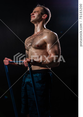 Man on black background keeps dumbbells pumped up in fitness sport, body strong hand, shirtless lifestyle. skin people fit With a ribbon in hand, the fitness gum is black Man on black background keeps dumbbells pumped up in fitness sport, body strong hand, shirtless lifestyle. skin people fit With a ribbon in hand, the fitness gum is black 78183200