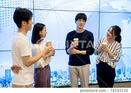 Young men and women chatting in front of a huge display 78183220