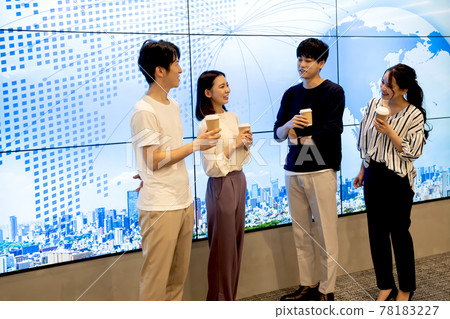 Young men and women chatting in front of a huge display 78183227