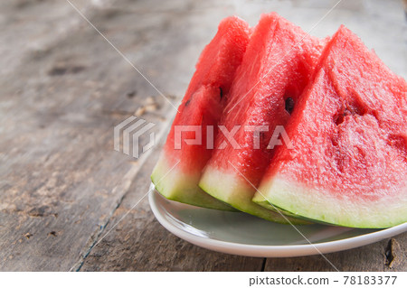 three slices of watermelon on a white plate on a wooden background three slices of watermelon on a white plate on a wooden background 78183377
