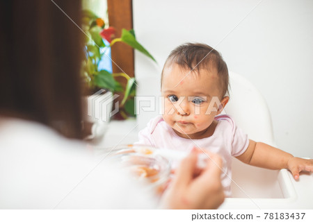 Mother feed her little daughter with a spoon Mother feed her little daughter with a spoon 78183437