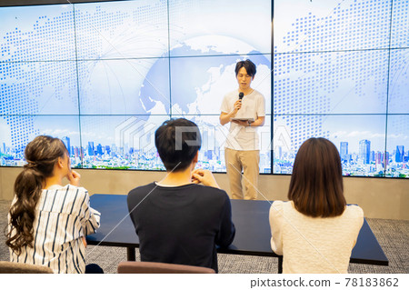 A young man giving a speech in front of a huge monitor A young man giving a speech in front of a huge monitor 78183862