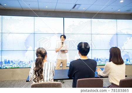 A young man giving a speech in front of a huge monitor A young man giving a speech in front of a huge monitor 78183865