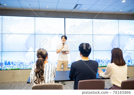 A young man giving a speech in front of a huge monitor A young man giving a speech in front of a huge monitor 78183866