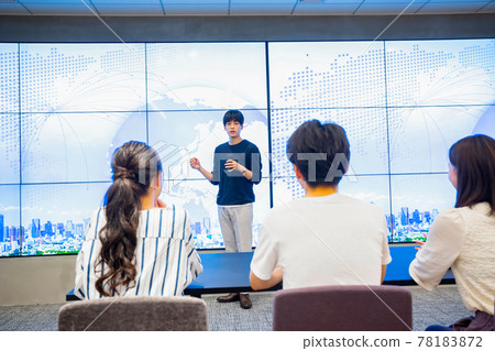 Young man giving a presentation in front of a huge monitor Young man giving a presentation in front of a huge monitor 78183872