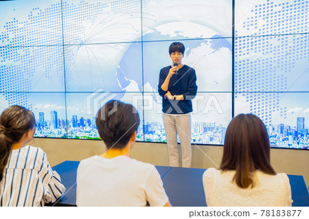 Young man giving a presentation in front of a huge monitor Young man giving a presentation in front of a huge monitor 78183877