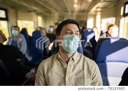 Man traveling by train wearing a facemask. Social distancing when traveling by railway during Covid-19 pandemic. Male commute to work in public transport train wearing face mask. New norm concept 78183985