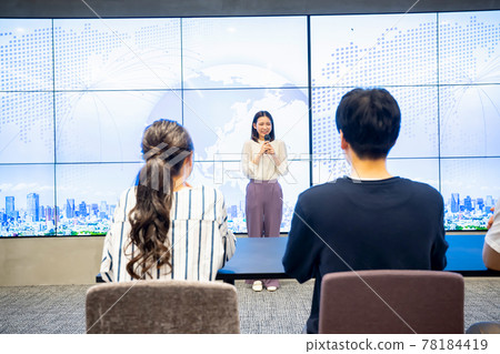 A young woman giving a presentation in front of a large vision A young woman giving a presentation in front of a large vision 78184419
