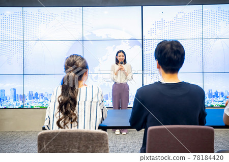 A young woman giving a presentation in front of a large vision A young woman giving a presentation in front of a large vision 78184420