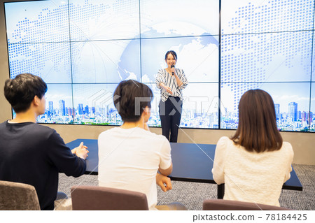 A young woman giving a speech in front of a large vision A young woman giving a speech in front of a large vision 78184425