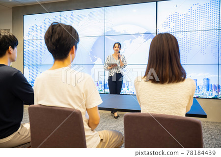 A young woman giving a speech in front of a large vision A young woman giving a speech in front of a large vision 78184439