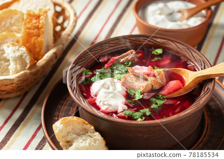 Freshly cooked hot homemade borscht - traditional dish of Russian and Ukrainian cuisine in earthenware dishes with bacon, bread, sour cream and garlic 78185534