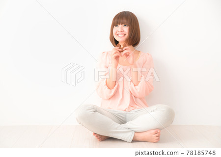 A young woman sitting cross-legged with a snack in her hands 78185748