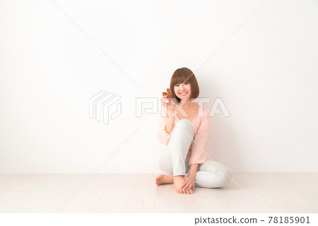 Young woman sitting on the floor with a snack Young woman sitting on the floor with a snack 78185901