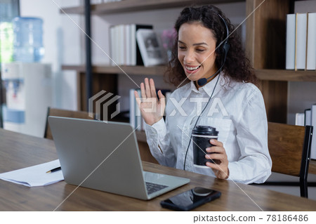 Beautiful woman wearing headset sitting at table hand motion having conversation online with laptop. Beautiful woman wearing headset sitting at table hand motion having conversation online with laptop. 78186486