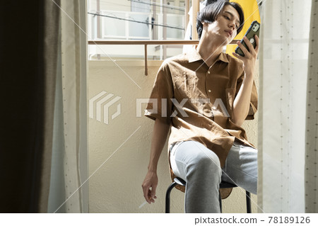 A man looking at a smartphone on the balcony 78189126