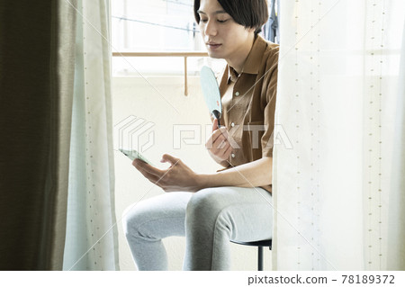 一個男人在陽台上看智能手機 78189372