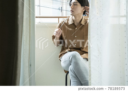 A man with a fan on the balcony 78189373