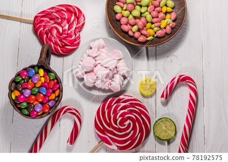 Colorful chocolate candies, lollipops, candy cane and marshmallows on wooden table 78192575