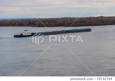 Tugboat pushing a heavy long barge on the river Dnieper 78192584