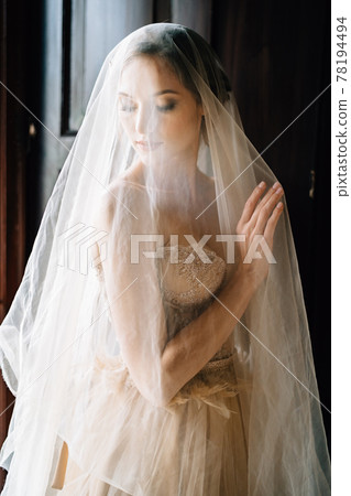 Bride in veil stands at the wall of an old villa with her head bowed. Lake Como Bride in veil stands at the wall of an old villa with her head bowed. Lake Como 78194494