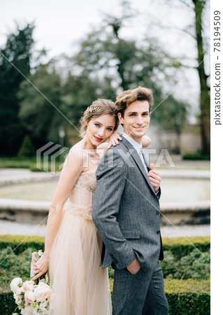 Bride rested her head on the groom's shoulder, hugging him from behind, in front of fountain. Lake Como, Italy. Close up Bride rested her head on the groom's shoulder, hugging him from behind, in front of fountain. Lake Como, Italy. Close up 78194509