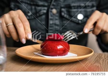 French mousse cake covered with red glaze on wooden background. Modern european cake pastry. Shallow French mousse cake covered with red glaze on wooden background. Modern european cake pastry. Shallow 78195733