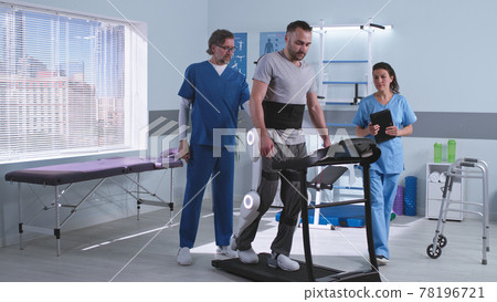 Doctors discussing rehabilitation results near patient in exoskeleton Doctors discussing rehabilitation results near patient in exoskeleton 78196721