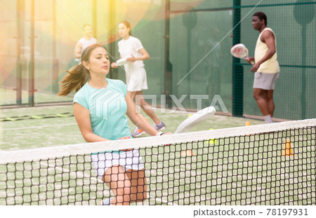 Training while playing on tennis court. Woman learning to play paddle Training while playing on tennis court. Woman learning to play paddle 78197931