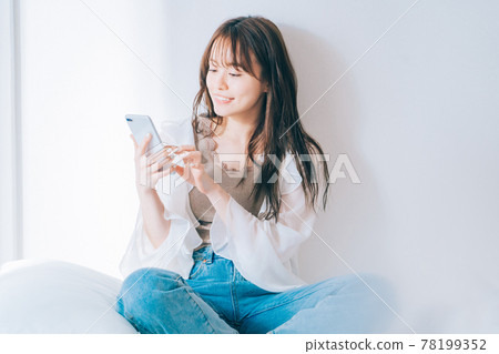 A young woman using a smartphone 78199352