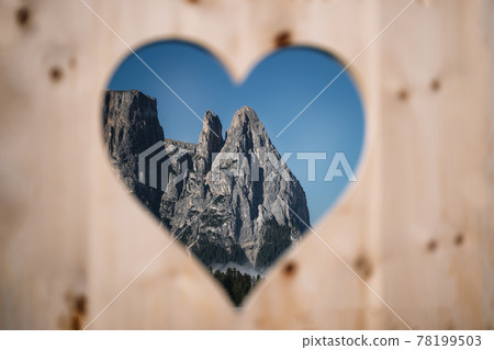 Pinnacles of Schlern view through the wooden heart. Seiser Alm, Dolomites Alps, Italy. With love from Dolomiti Pinnacles of Schlern view through the wooden heart. Seiser Alm, Dolomites Alps, Italy. With love from Dolomiti 78199503