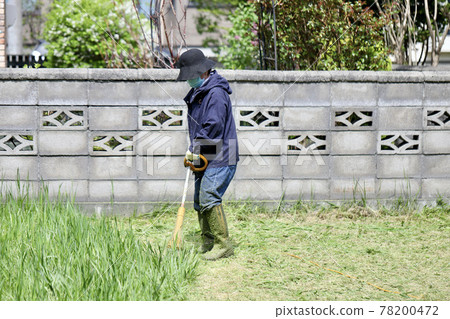 一位中年婦女用家用電動割草機割花園 78200472