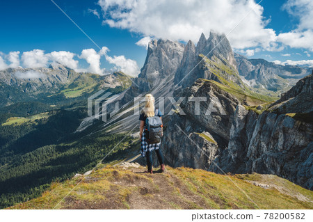 Adult women with backpack enjoy landscape of Seceda peak in Dolomites Alps, Odle mountain range, South Tyrol, Italy, Europe. Travel vacation concept 78200582