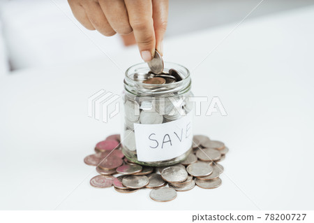 women hand putting money coin into glass jar for saving money. saving money and financial concept women hand putting money coin into glass jar for saving money. saving money and financial concept 78200727