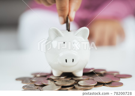 Close up of woman hand putting money coin into piggy bank for saving money. saving money and financial concept 78200728
