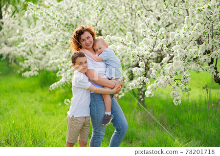 mother with sons in flowering garden. youngest child in her arms 78201718