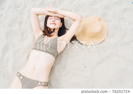 一個穿泳衣的女人躺在沙灘上 一個穿泳衣的女人躺在沙灘上 78201724