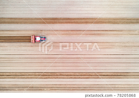 Lonely tractor on agricultural field with rows of plowed soil Lonely tractor on agricultural field with rows of plowed soil 78205868