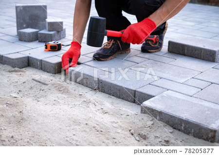 The master in yellow gloves lays paving stones 78205877