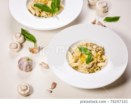 Homemade appetizing penne pasta with mushrooms, cheese parmesan creamy sauce and fresh basil. Traditional Mediterranean cuisine. Two servings on a light background. Top view. Copy space 78207181