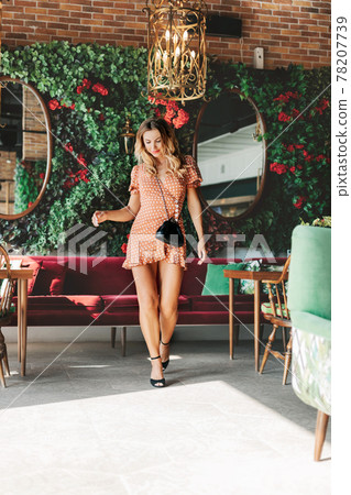 A beautiful girl smiles thoughtfully as she leaves a modern cafe. A satisfied customer leaves the restaurant 78207739
