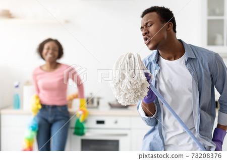 Funny black guy using mop as microphone, singing while cleaning Funny black guy using mop as microphone, singing while cleaning 78208376