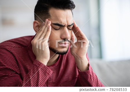 Upset middle-eastern guy suffering from headache, closeup Upset middle-eastern guy suffering from headache, closeup 78208533
