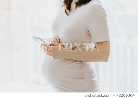 Pregnant woman holding mobile phone 78209304